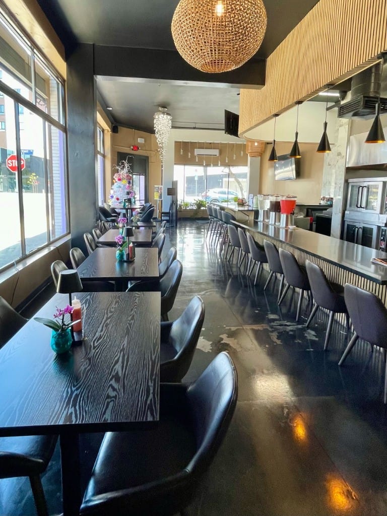 Full dining room view with bar seating and chandelier