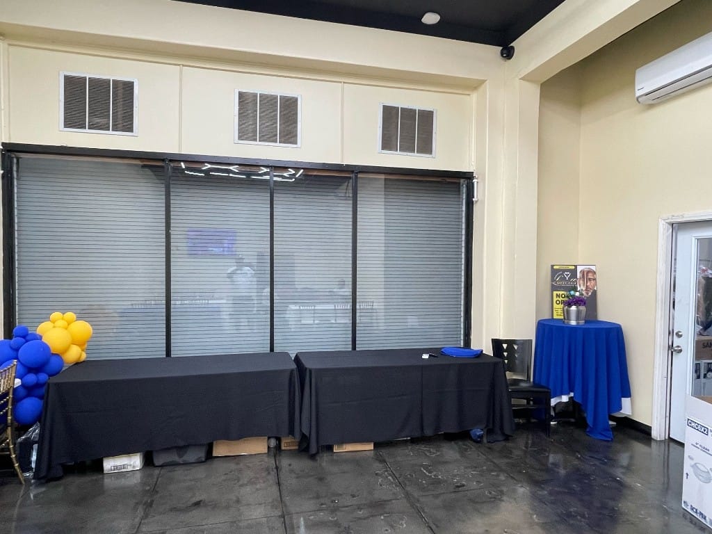 Event space with black banquet tables, blue cocktail table, and balloon decor